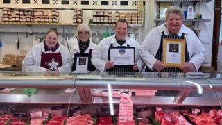 Tim Potter and his team standing behind butcher counter with awards. 