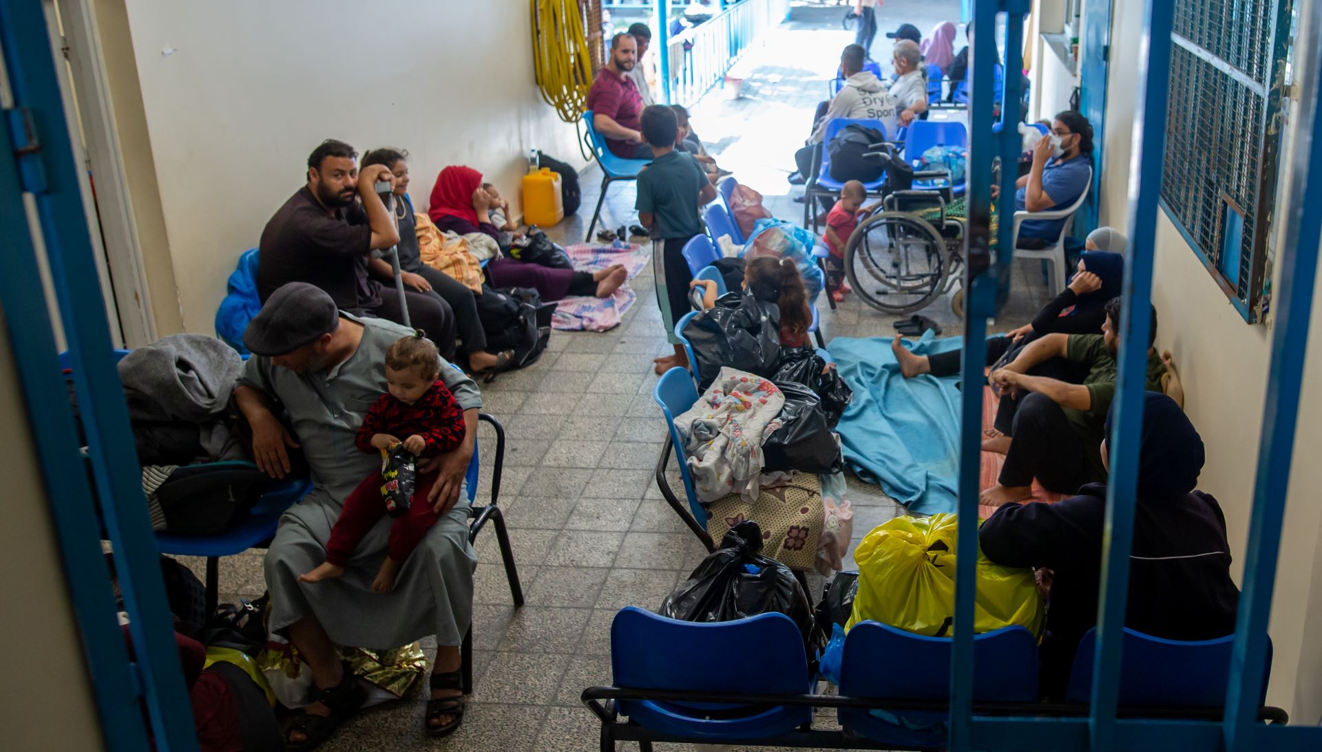 People crowded into the corridor of a hospital, many sitting on the floor