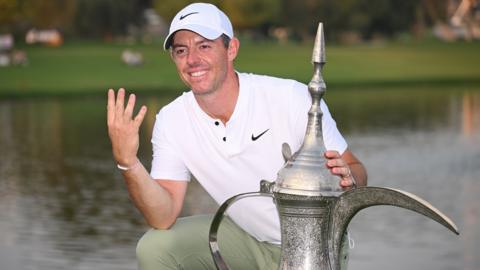 Rory McIlroy, holding up four fingers, with the Dubai Desert Classic trophy