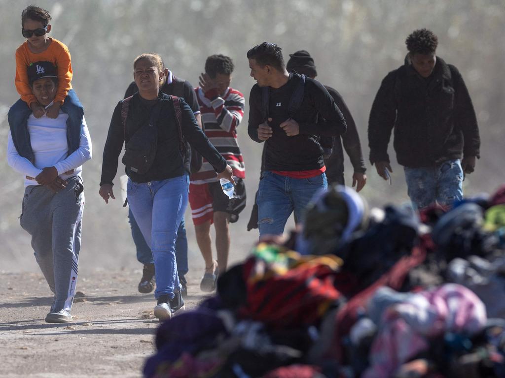 EAGLE PASS, TEXAS - JANUARY 08: Immigrants from Venezuela walk past a pile of discarded migrant clothing after crossing the Rio Grande into the United States on January 08, 2024 in Eagle Pass, Texas. Immigrant crossings in the area have dipped dramatically since a major surge in the last months of 2023.   John Moore/Getty Images/AFP (Photo by JOHN MOORE / GETTY IMAGES NORTH AMERICA / Getty Images via AFP)