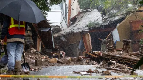 A man in Southern California stands outside a home destroyed by a powerful storm