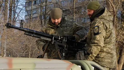 Two Ukrainian servicemen check an anti-aircraft machine gun