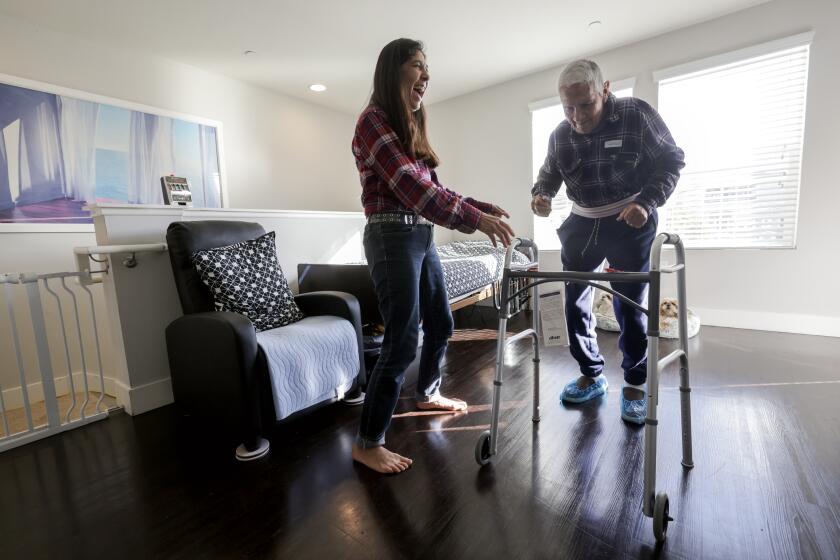 SAN DIEGO, CA - FEBRUARY 09, 2024: In-Home Supportive Services recipient, Agustine Galvan, 83, who is suffering from dementia due to Alzheimer's, dances to Cumbia music being played on a phone with his daughter, Norma Galvan, a provider with IHSS, while in their home in San Diego on Friday, February 09, 2024.