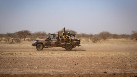 Burkina Faso soldiers patrol aboard a pick-up truck on the road from Dori to the Goudebo refugee camp, in the country's restive north, in this file photo taken in February 2020.