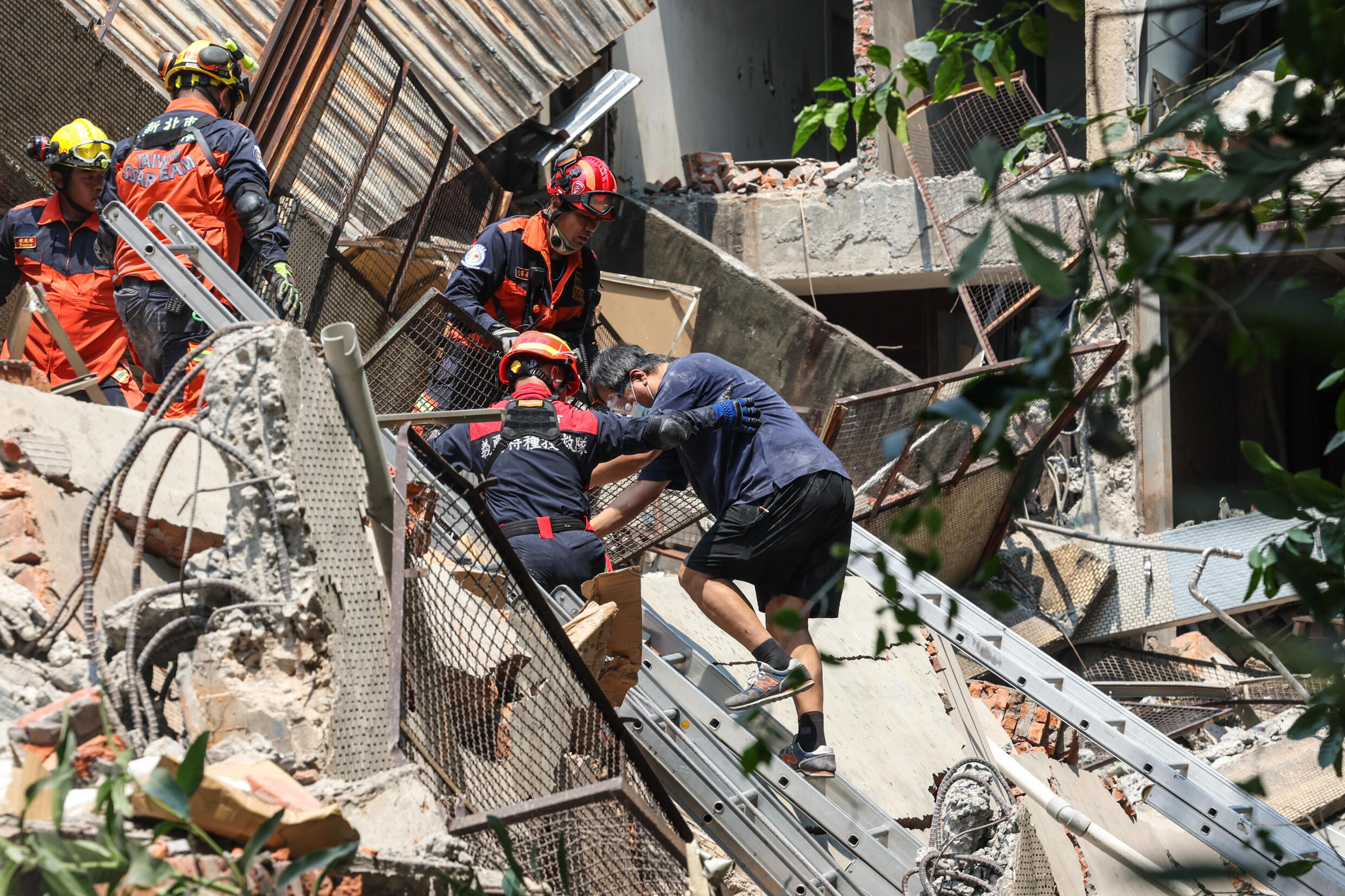 A Central News Agency photo shows emergency workers assisting a survivor after he was rescued from a damaged building in New Taipei City