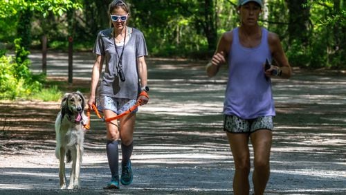 Christina Mathers walks Corra (left) at the Cochran Shoals Unit-Interstate North of the Chattahoochee River National Recreation Area in Cobb County on Thursday, April 18, 2024. (Photo by John Spink/AJC)