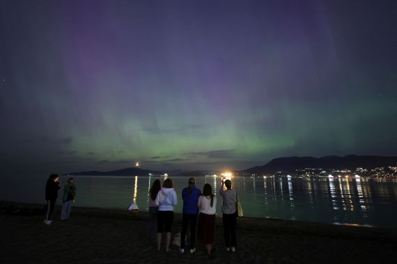 The aurora borealis, also known as the "northern lights", caused by a coronal mass ejection on the Sun, illuminates the sky over Jericho Beach in Vancouver, British Columbi