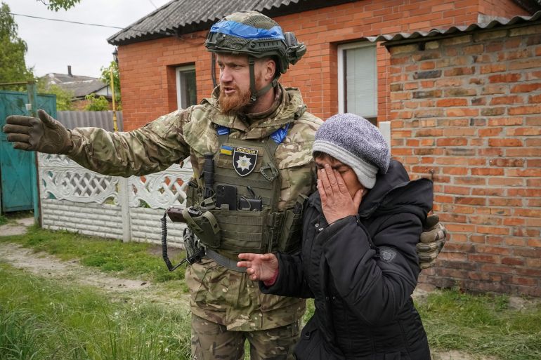 A police officer helps a local resident during an evacuation due to Russian shelling in the town of Vovchansk in Kharkiv region