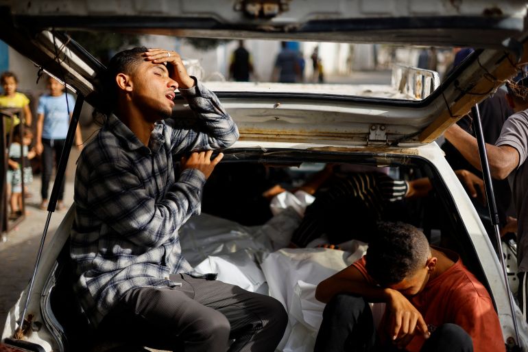 Mourners react next to the bodies of Palestinians killed in an Israeli strike on an area designated for displaced people, during their funeral in Rafah