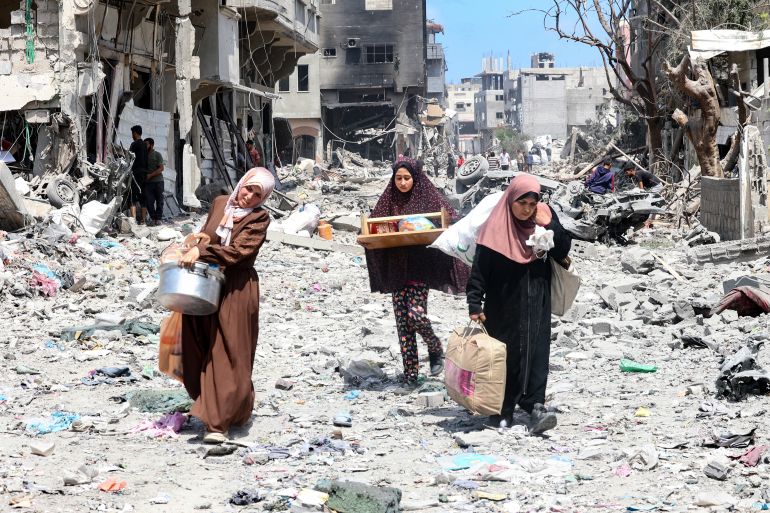 People carry some belongings as they walk through a debris-strewn street in the al-Zaitoun neighbourhood of Gaza City in the northern part of the Palestinian territory on May 15, 2024, amid the ongoing conflict between Israel and the militant Hamas movement. (Photo by AFP)