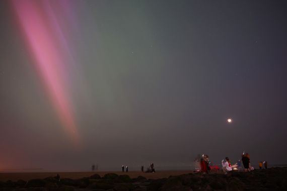 People gather to watch the Aurora Borealis, also known as the Northern Lights, in New Brighton in northwest England late on May 10