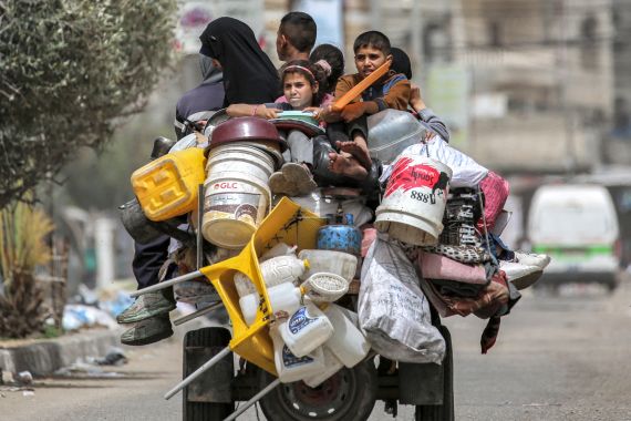 A man, woman, and children ride in the back of a tricycle loaded with belongings and other items as they flee bound for Khan Yunis, in Rafah in the southern Gaza Strip on May 11