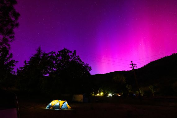 Northern lights or aurora borealis illuminate the night sky over a camper's tent north of San Francisco in Middletown, California on May 11
