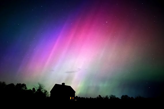 The northern lights flare in the sky over a farmhouse, late Friday, May 10, 2024, in Brunswick, Maine