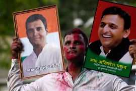 A Samajwadi Party supporter carries portraits of party leader Akhilesh Yadav, right, and Congress party leader Rahul Gandhi [Rajesh Kumar Singh/AP Photo]