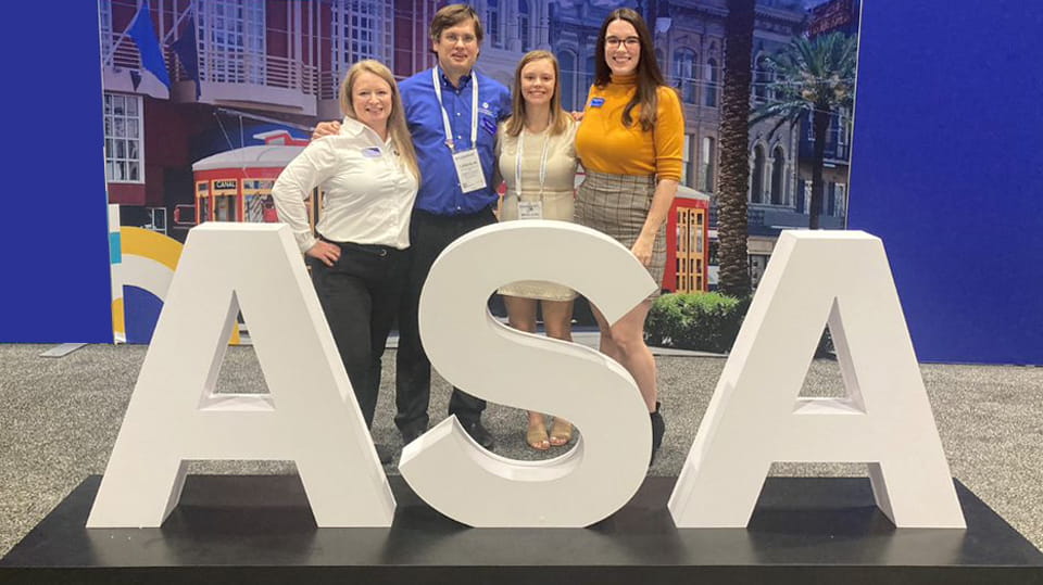 Employees enjoy a group photo opportunity with the ASA sign the annual meeting