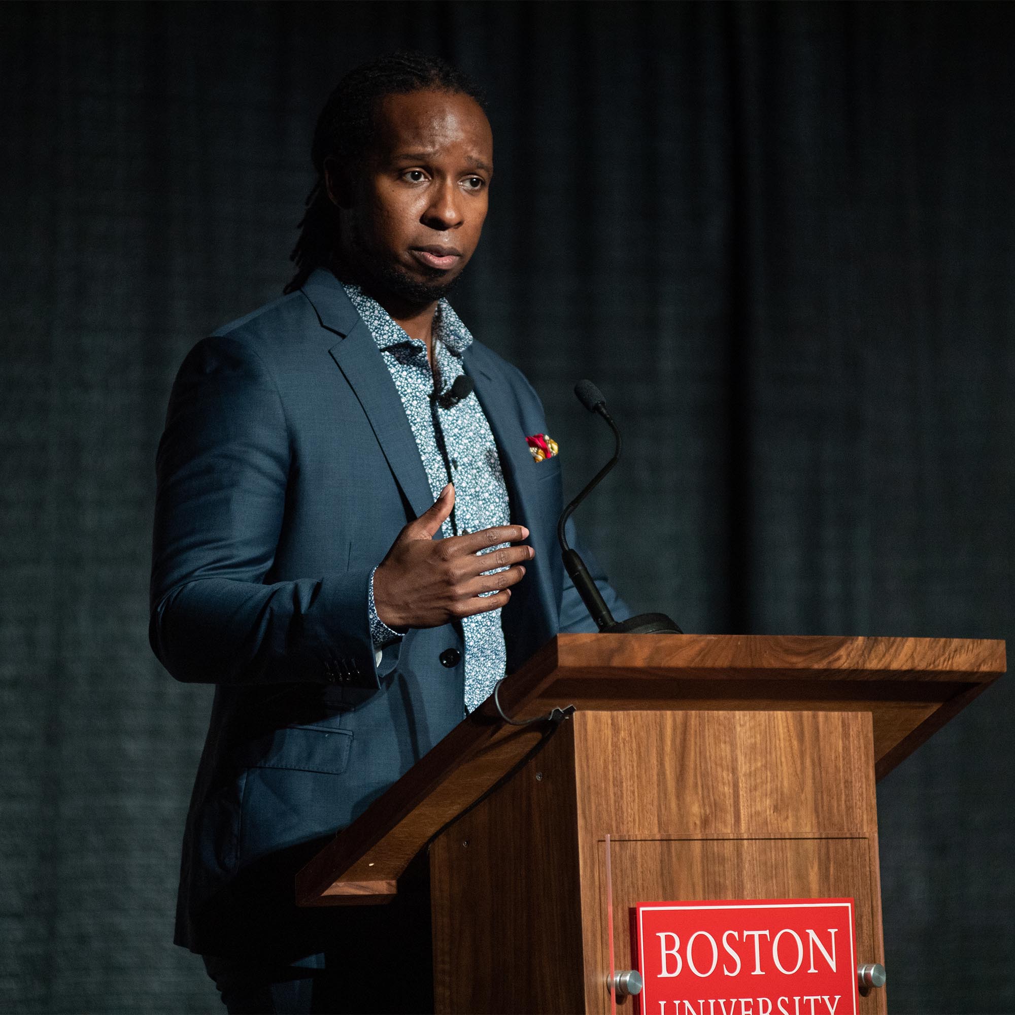 Photo: Dr Ibram X Kendi, a black man with dreadlocks wearing a suit and tie, at What the Science Tells Us: Racial Health and Economic Inequities during the Pandemic Symposium presented by The BU Center for Antiracist Research in the Metcalf Hall October 1. Photo by Cydney Scott