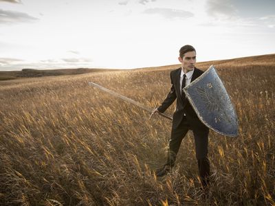 Businessman with sword and shield outdoor.