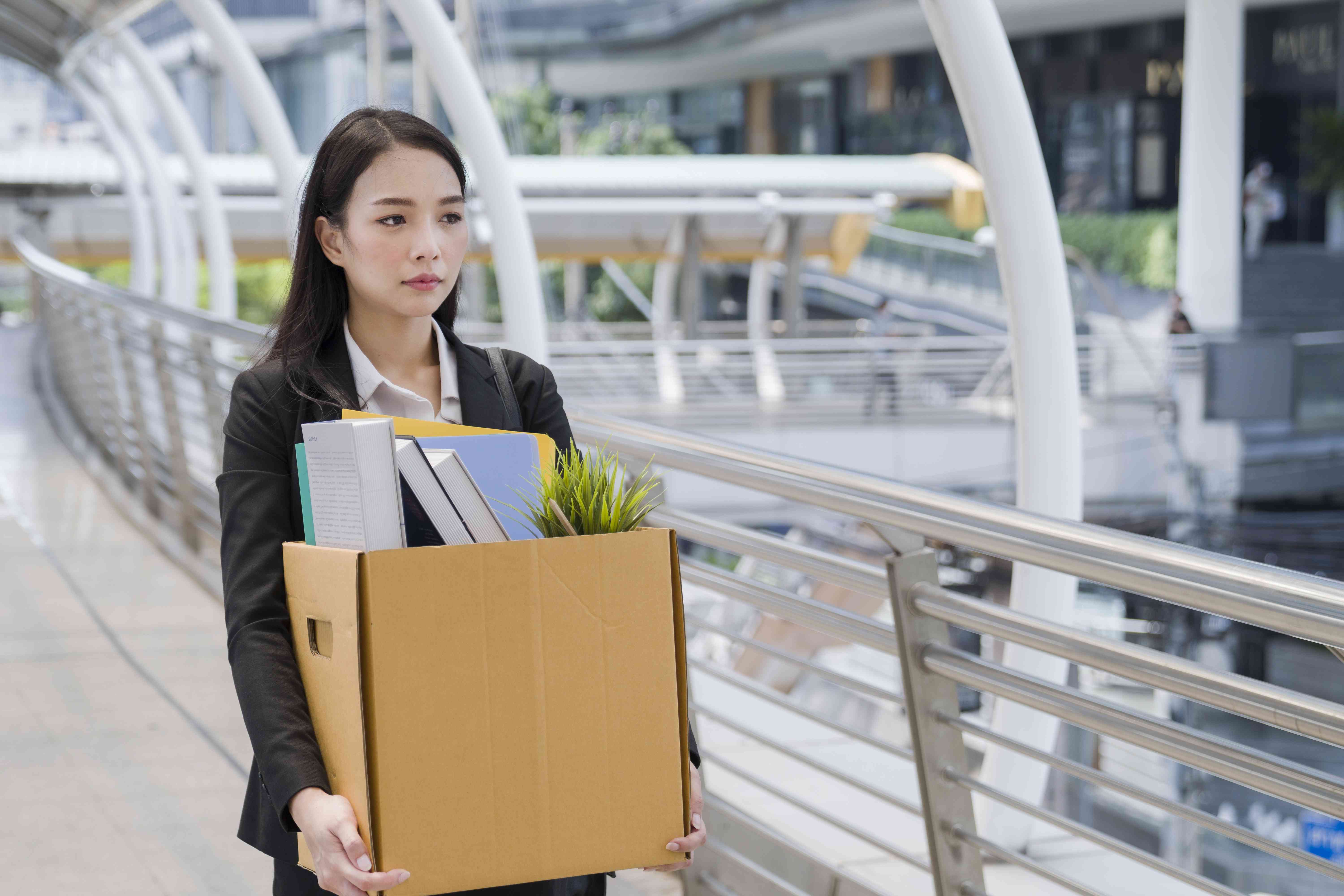 Woman carrying a box of work supplies away from an office building