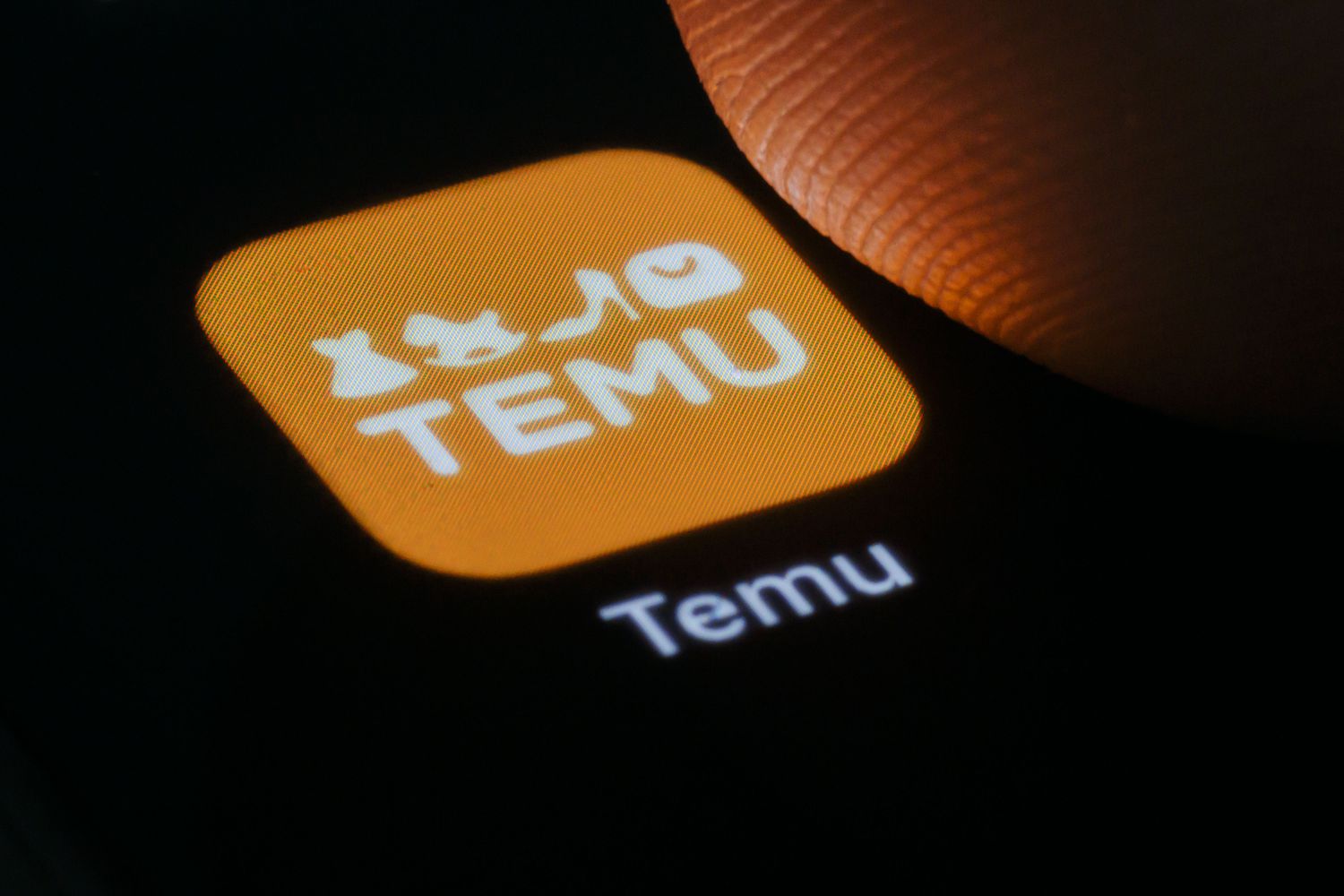 In this photo illustration the logo of app Temu, an online marketplace from the Chinese company PDD Holdings can be seen on a smartphone next to a finger on March 27, 2024 in Berlin, Germany