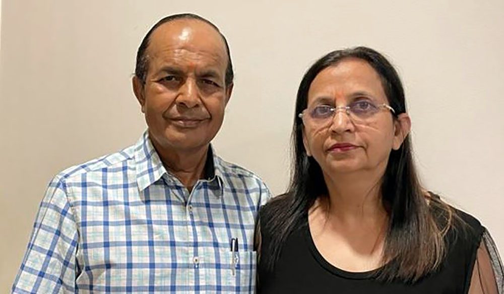 Naresh Aggarwal, M.D., stands in front of a white wall beside his wife, Usha