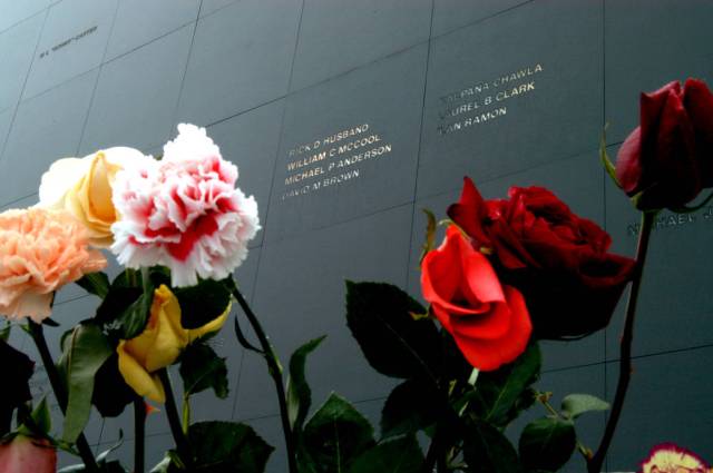 Flowers frame the names of the STS-107 crew carved onto the black granite surface of the Astronaut Memorial Mirror at the Kennedy Space Center Visitor Complex