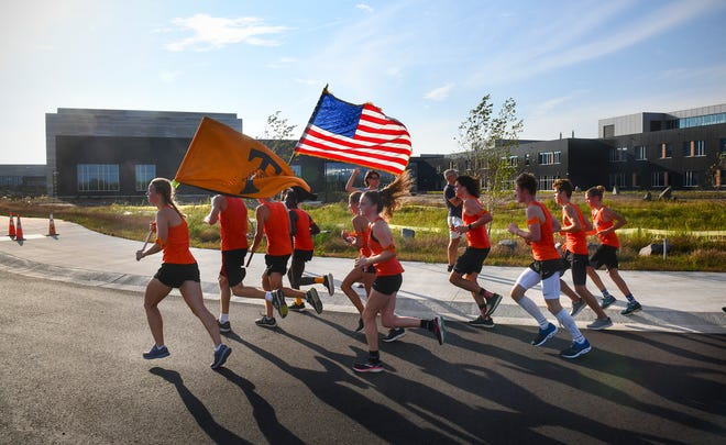 Members of the Tech cross country team carry flags and a torch to the new school building before the start of the grand opening ceremony for the new high school Monday, Sept. 16, 2019, in St. Cloud. The runners started at the old Tech building.