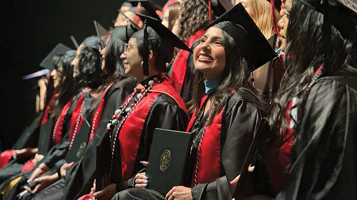 SDSU alumna Zoila Gonzalez smiles from the stage during her commencement ceremony.