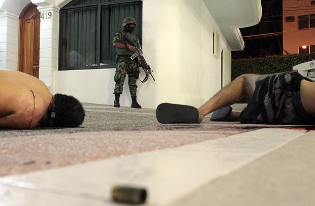 15 March: A member of the Mexican Navy stands before the bodies of two alleged drug traffickers who died in a shoot-out at the Costa Azul Hotel in the resort city of Acapulco