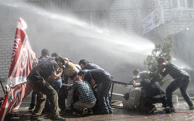 Left-wing militants protect themselves as Turkish anti-riot police fires water cannon to disperse a demonstration in Istanbul's Gazi district, on July 26, 2015.