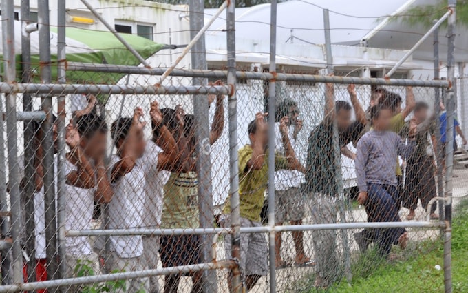 Asylum seekers staring at media from behind a fence at the Oscar compound in the Manus Island detention centre, Papua New Guinea, 21 March 2014 