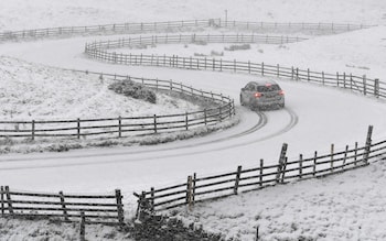 A car is driven on a snow-covered road on Mam Tor near Castleton, central England 