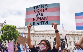 A protester holds a placard with the colours of the trans pride flag during a demonstration