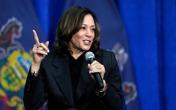 Ms Harris wears black, holds a microphone and gestures with an index finger