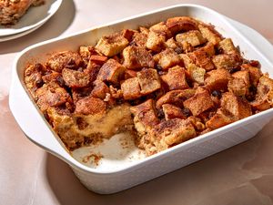 A baking dish of bread pudding, topped with cinnamon sugar, with a serving cut out