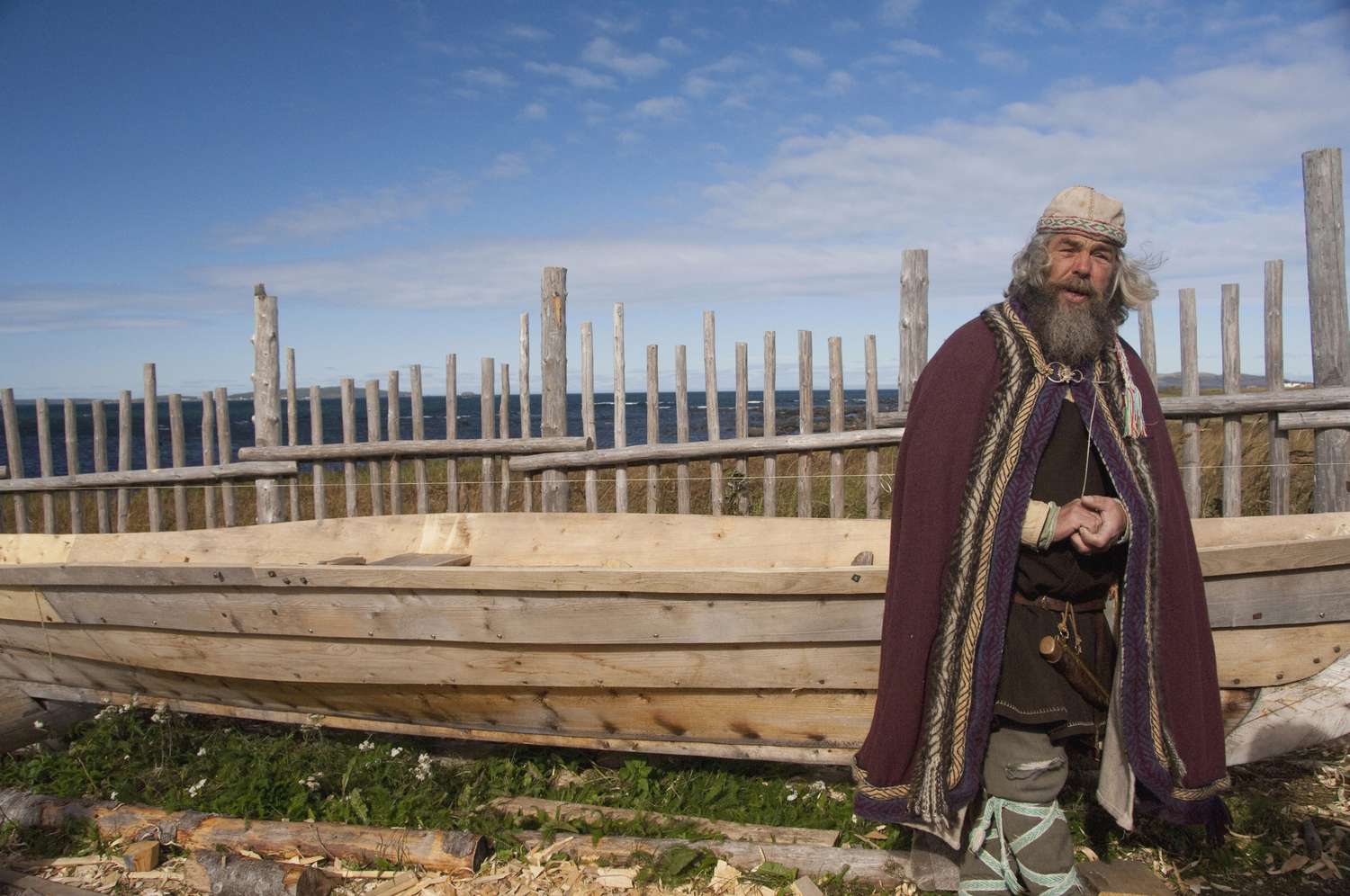 Viking actor in typical attire in front of longboat replica, L'Anse Aux Meadows, Newfoundland