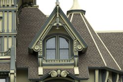 ornate gable dormer in green and cream colors, double arched windows, on steep roofed tower