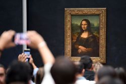 Visitors take pictures in front of the Mona Lisa