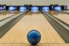 Blue bowling ball in center of alley