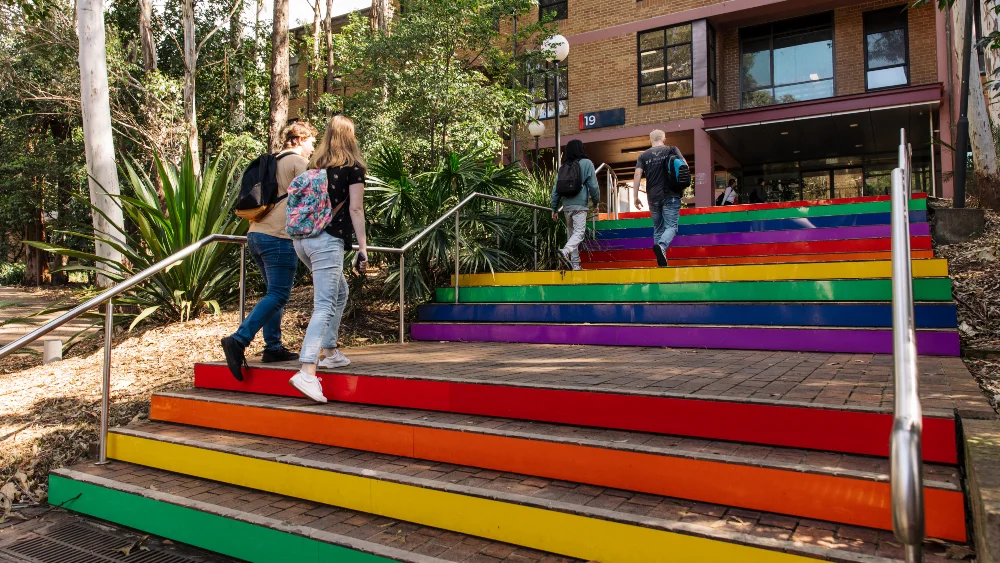 Students walking on rainbow painted stairs at Wollongong Campus.