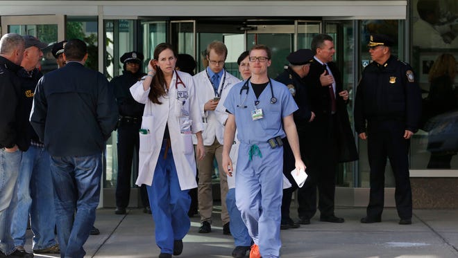 Medical personnel walk past law enforcement officials, right, as they depart the site of a shooting Jan. 20, 2015, at Brigham and Women's Hospital, in Boston.