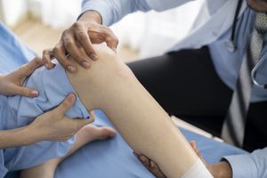 A healthcare provider examines the leg of a person 