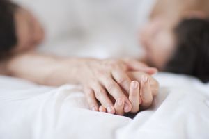 Couple holding hands in bed
