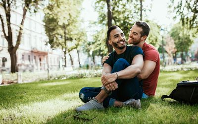Gay couple - Latino and European millennial men - enjoying in park in summer - stock photo