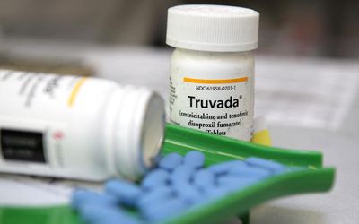 bottle of Truvada with blue pills in front on it