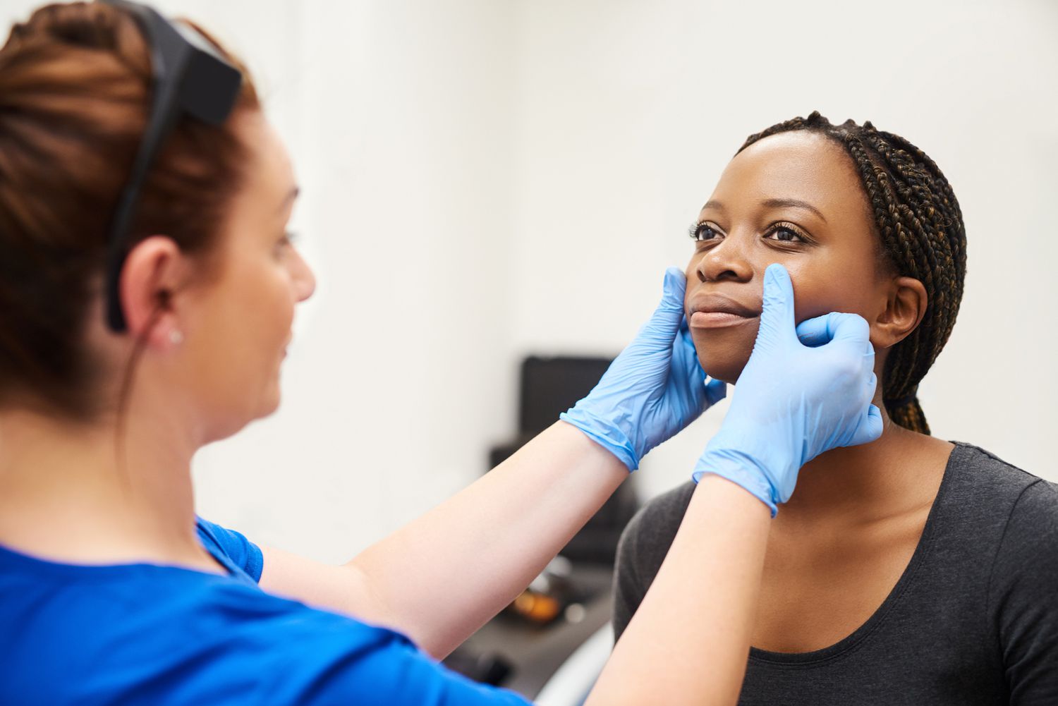 Dermatologist looking at young woman's skin