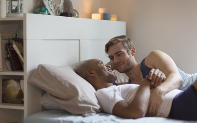 Male couple lying in bed together, face to face