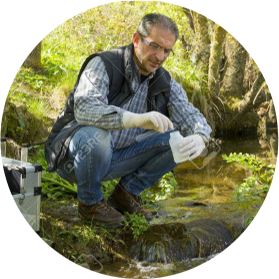 A water scientist taking a sample from a stream.