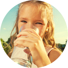 A young girl drinking a glass of clean drinking water