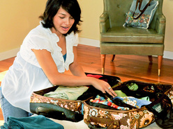 pregnant woman kneeling on floor and packing suitcase